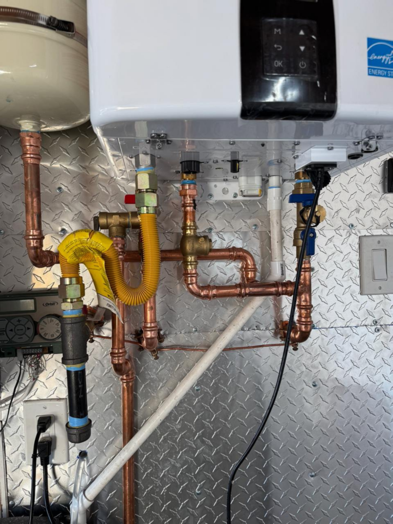 Piping under the gas water heater on a metal wall.