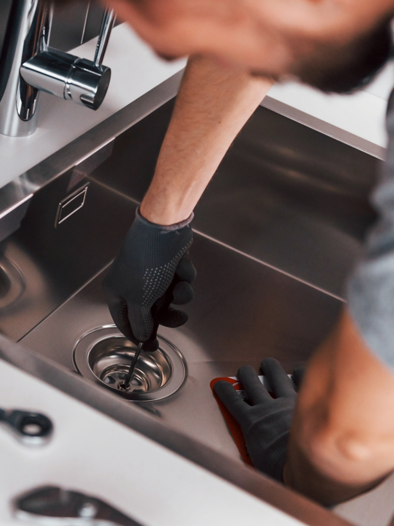 The plumber is installing the drain in the new kitchen sink.