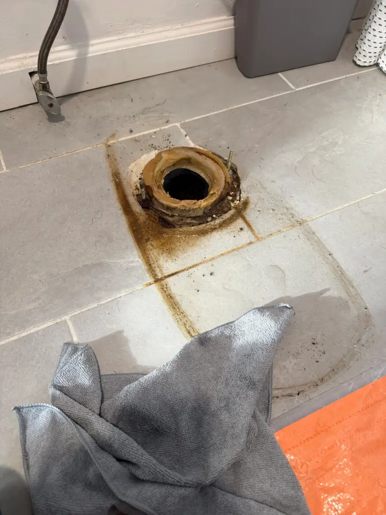 Plumber repairing a leak beneath kitchen plumbing