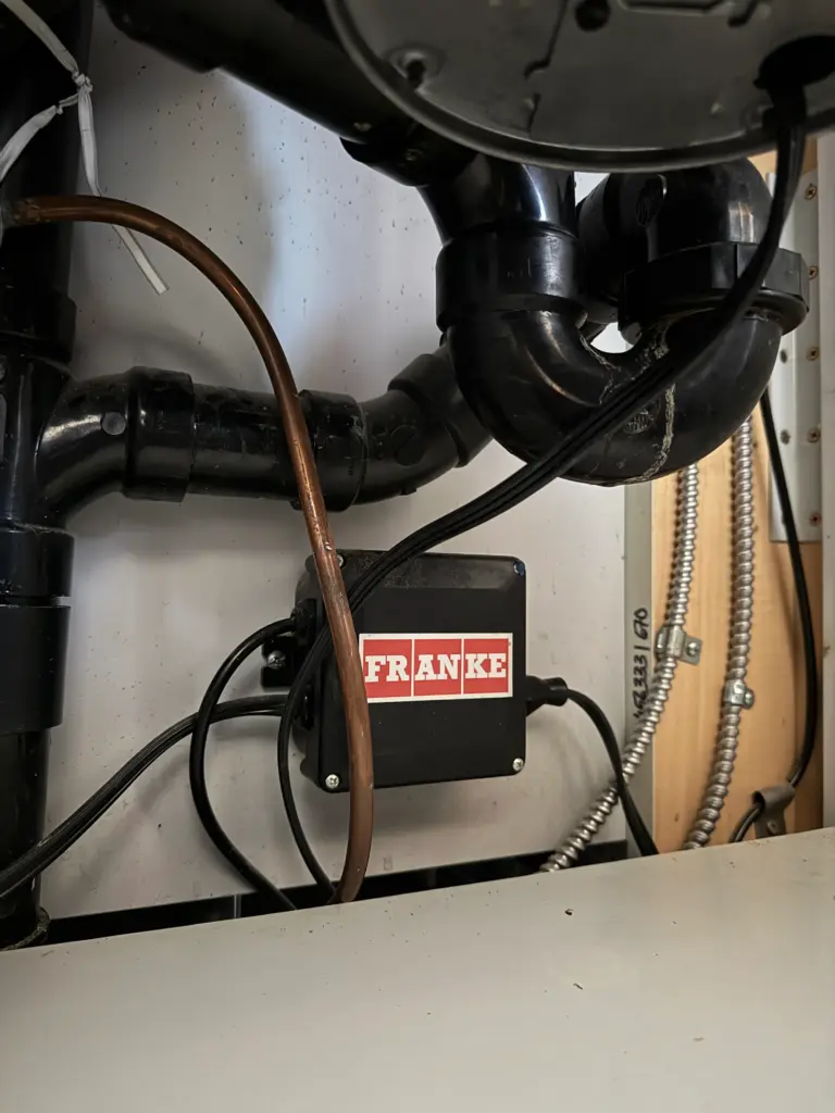 Kitchen sink P-trap being repaired beneath a cabinet