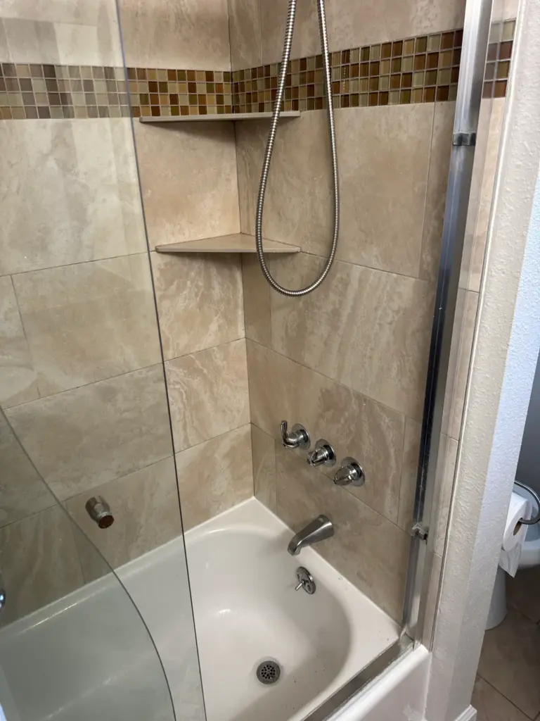 Plumber replacing a shower valve behind a tiled wall