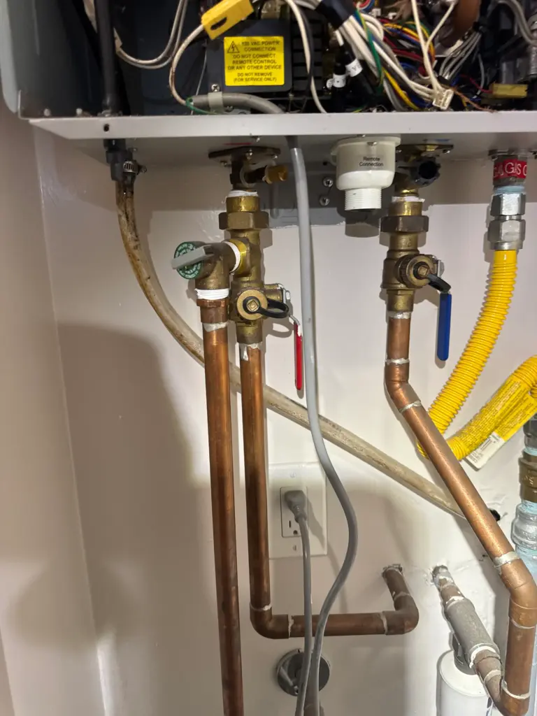 Plumber servicing tankless water heater piping and valves