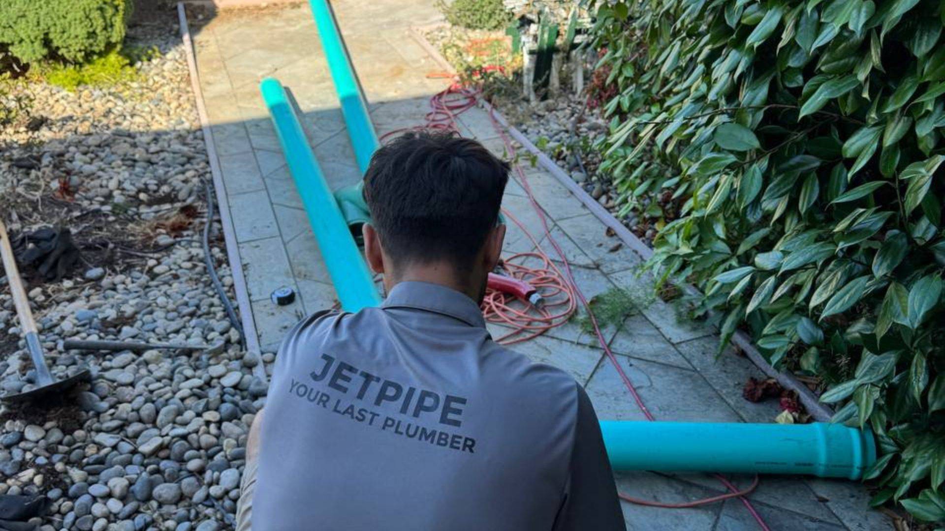 Plumber repairing an exposed sewer line in a trench